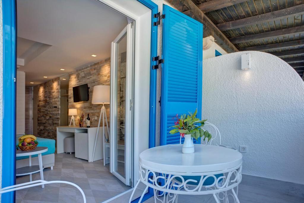 Room balcony with table and chairs beside blue shutters