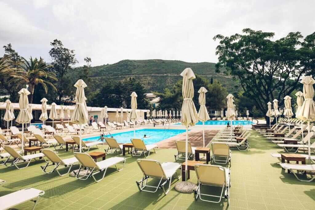 Pool terrace with sun loungers and green hills behind
